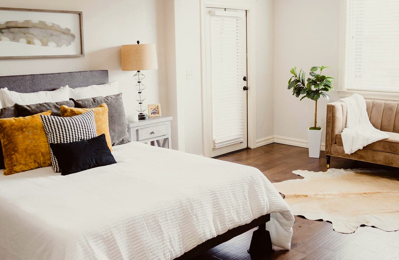A white room with a tall garden door standing open to green